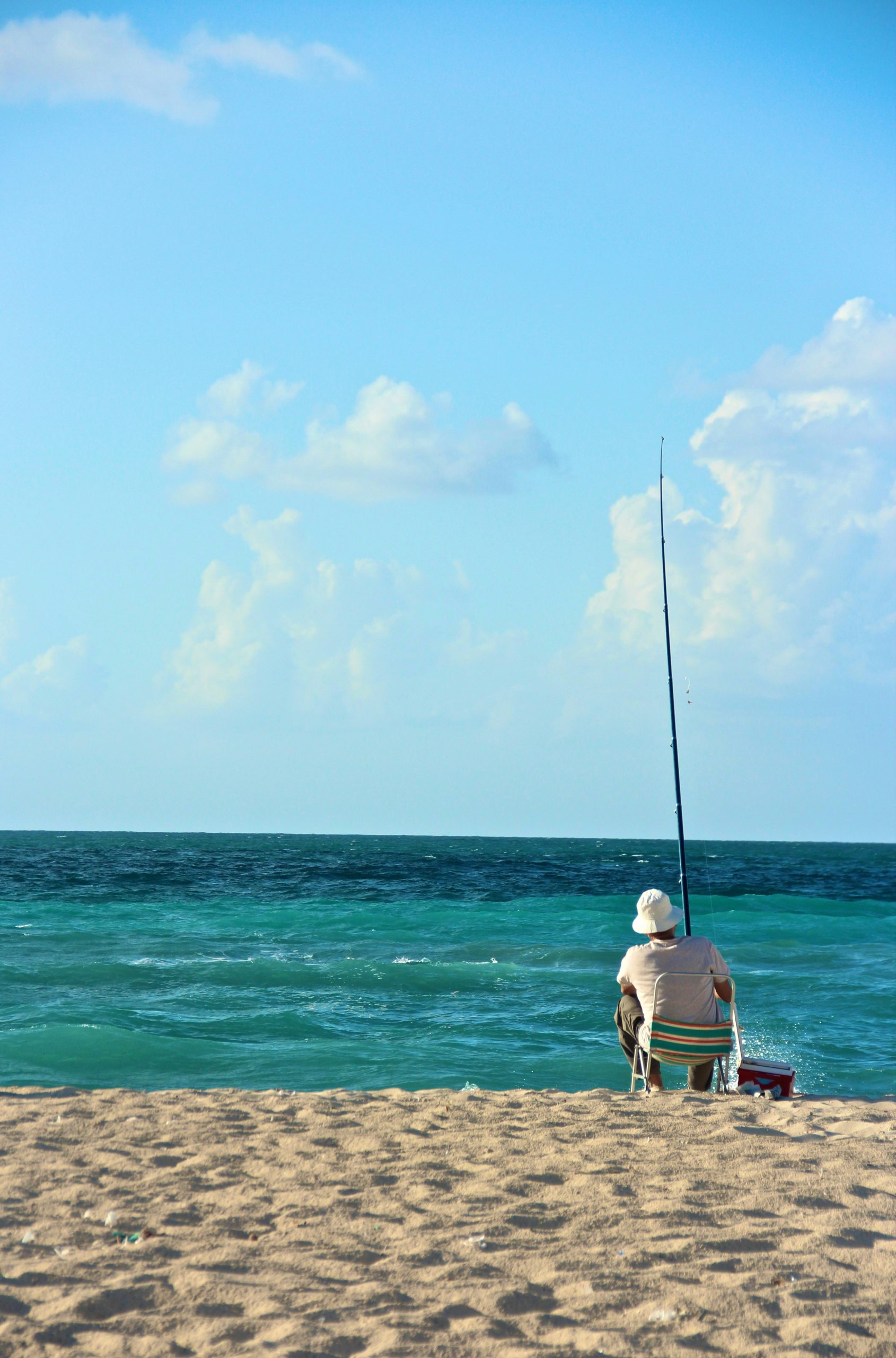 A guy fishing on the beach. With solar water panels you can enjoy it for a longer time.