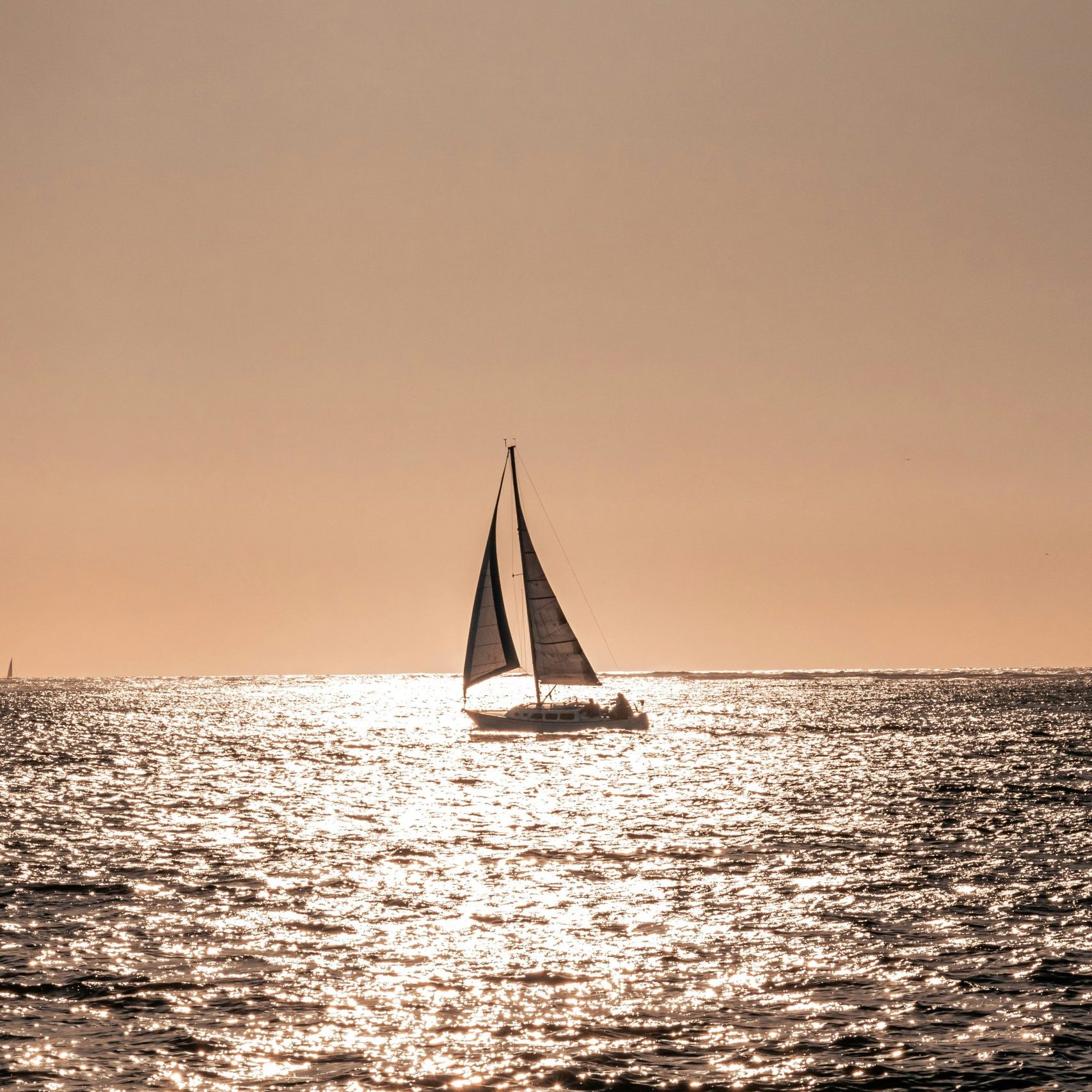 A sailboat in sunset using solar water panels for energy on board